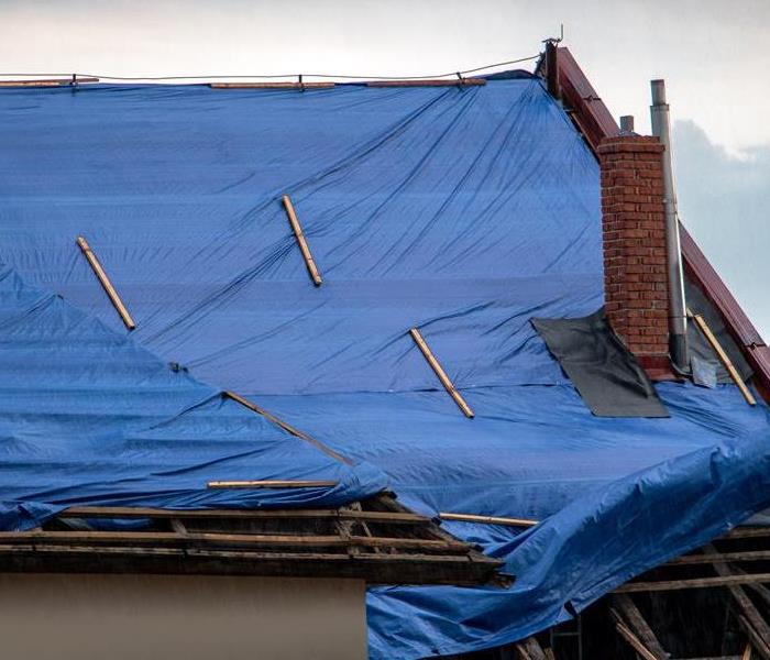 A roof is covered in tarp after storm damage.
