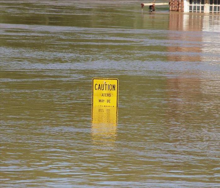 a caution road signage halfway consumed by storm flood